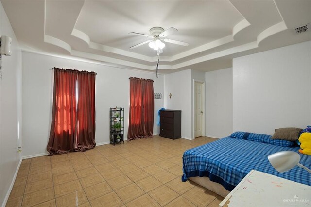 tiled bedroom featuring a tray ceiling and ceiling fan