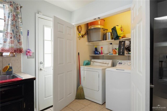 laundry room with light tile patterned flooring, independent washer and dryer, and sink