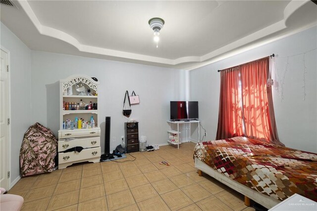 tiled bedroom featuring a tray ceiling