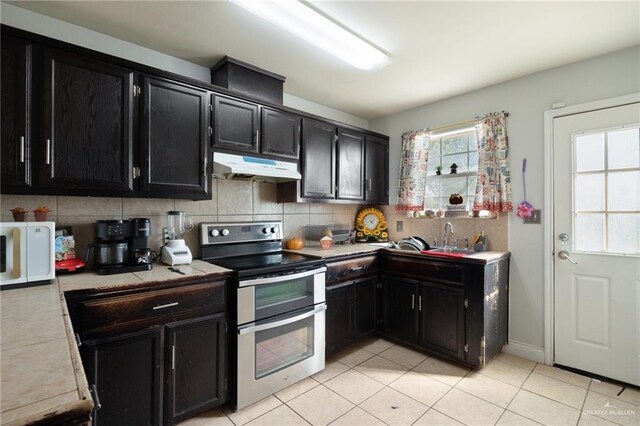 kitchen with backsplash, sink, light tile patterned floors, and stainless steel range with electric cooktop