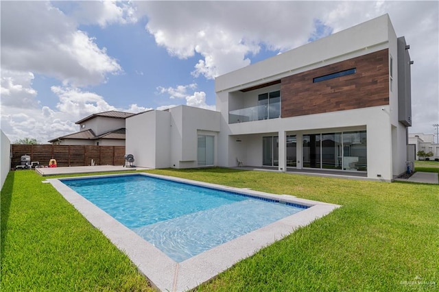 rear view of house with a fenced in pool and a yard