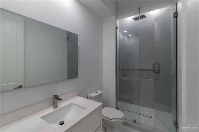 bathroom featuring vanity, a shower with shower door, and toilet