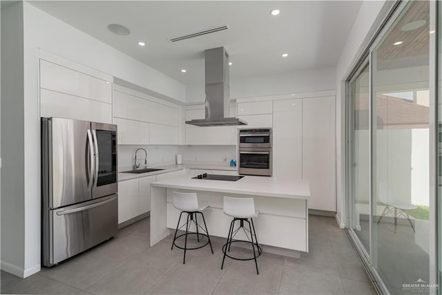 kitchen with island exhaust hood, sink, white cabinets, and stainless steel appliances