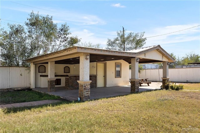 back of property with exterior bar, a lawn, and a patio