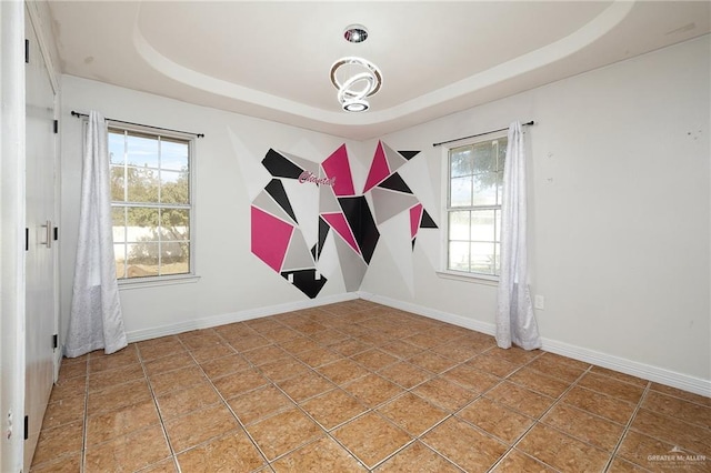 tiled spare room featuring a raised ceiling