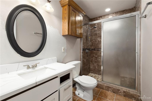 bathroom with a shower with shower door, toilet, and vanity