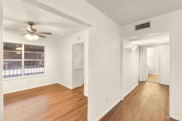 interior space featuring ceiling fan, wood-type flooring, and a textured ceiling