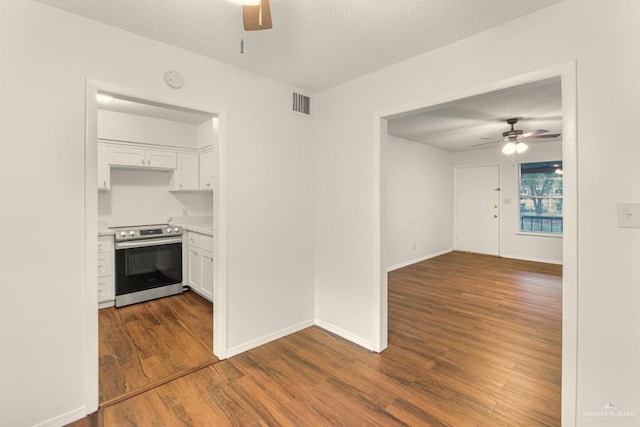 kitchen with white cabinetry, wood-type flooring, stainless steel range with electric cooktop, and ceiling fan