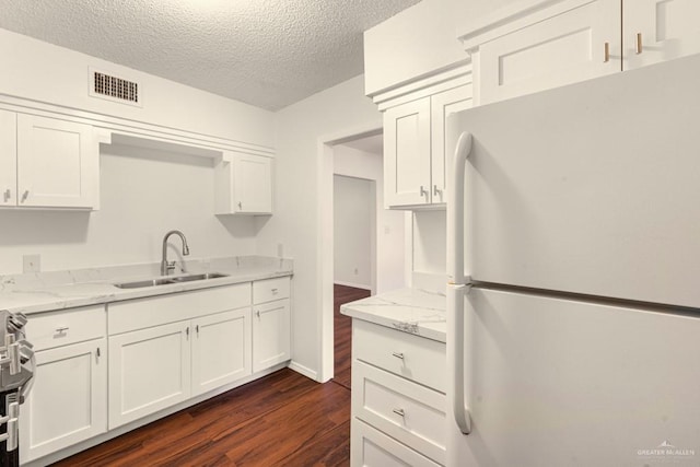 kitchen featuring sink, light stone counters, white cabinetry, dark hardwood / wood-style flooring, and white fridge