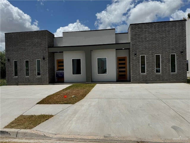 contemporary home featuring brick siding and stucco siding