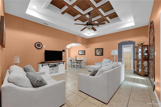 tiled living room with coffered ceiling, ceiling fan, and a high ceiling