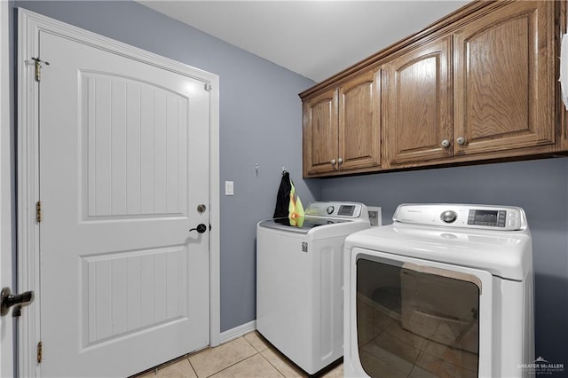 washroom featuring light tile patterned flooring, cabinets, and washer and clothes dryer