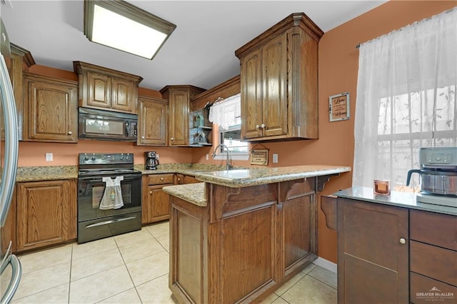 kitchen with black appliances, sink, light tile patterned floors, kitchen peninsula, and light stone countertops