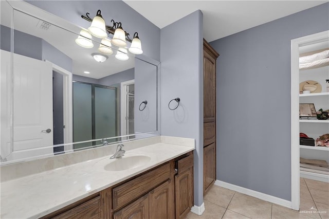 bathroom with a chandelier, vanity, a shower with shower door, and tile patterned flooring