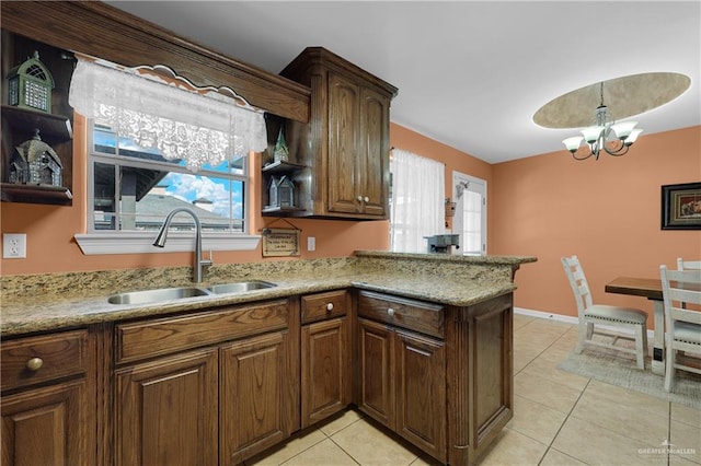 kitchen with sink, light tile patterned floors, a notable chandelier, light stone countertops, and kitchen peninsula