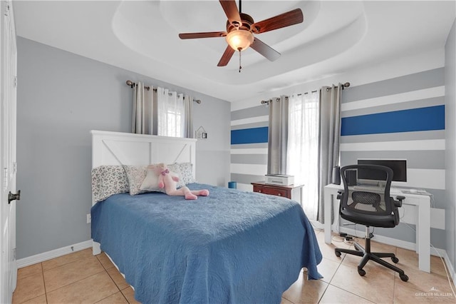 bedroom featuring ceiling fan, a raised ceiling, multiple windows, and light tile patterned floors