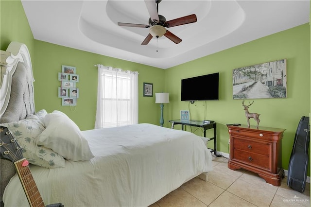 tiled bedroom with ceiling fan and a tray ceiling