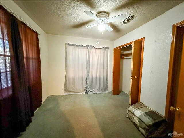 bedroom with ceiling fan, carpet floors, and a textured ceiling