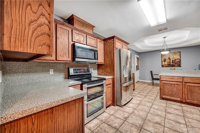 kitchen featuring pendant lighting, a raised ceiling, appliances with stainless steel finishes, tasteful backsplash, and light tile patterned flooring