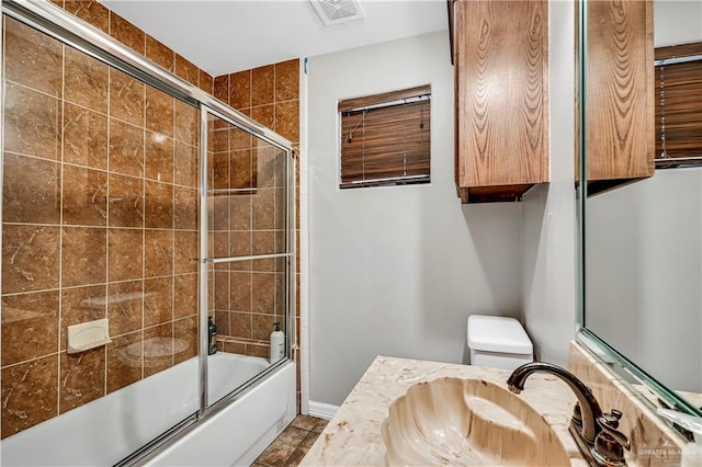 full bathroom featuring vanity, toilet, and enclosed tub / shower combo