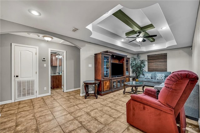 living room with ceiling fan, a raised ceiling, and tile patterned flooring