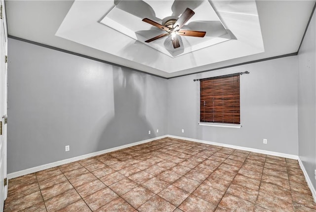 tiled spare room featuring a raised ceiling, ceiling fan, and ornamental molding