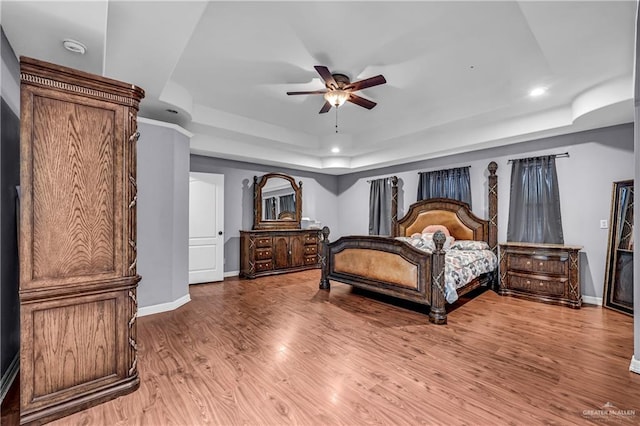 bedroom featuring ceiling fan, hardwood / wood-style flooring, and a tray ceiling