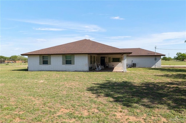 back of house with brick siding, a lawn, and central air condition unit