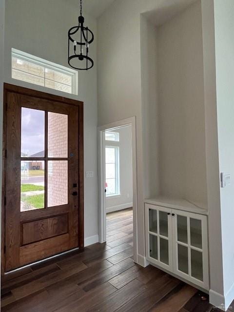 entryway with a towering ceiling, dark wood-type flooring, and a chandelier