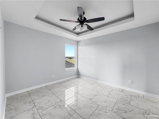 empty room featuring a tray ceiling and ceiling fan