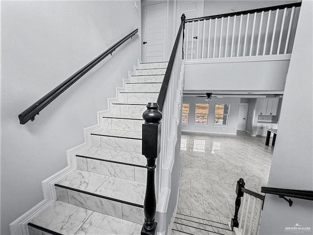 staircase featuring ceiling fan and a high ceiling