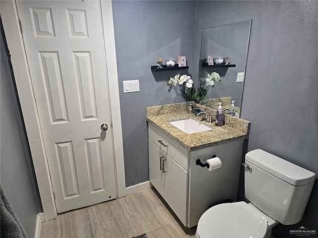 bathroom with toilet, vanity, and hardwood / wood-style flooring