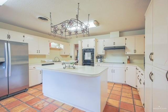 kitchen featuring light countertops, under cabinet range hood, black appliances, and visible vents