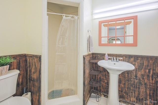 bathroom featuring tile patterned floors, wainscoting, toilet, and a shower with shower curtain