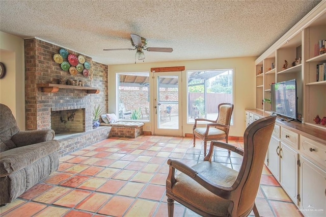 interior space with a ceiling fan, a textured ceiling, a wealth of natural light, and a fireplace