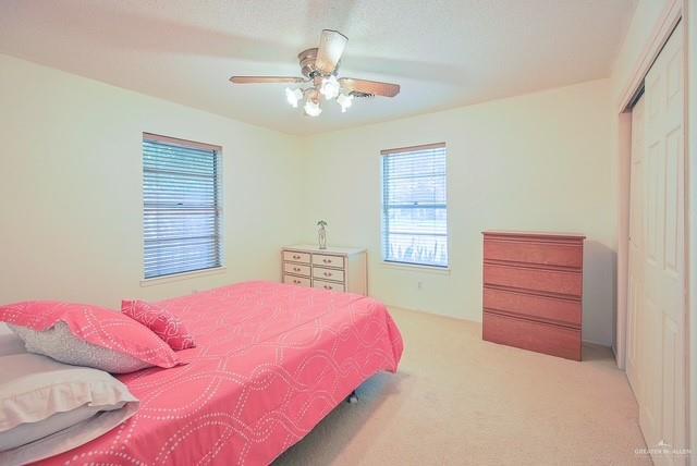 bedroom with ceiling fan, carpet, and a closet