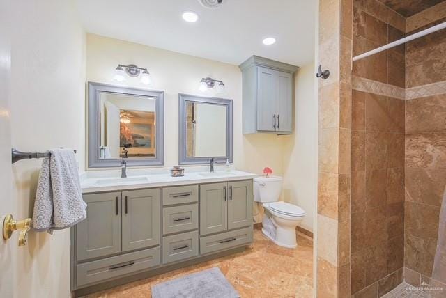 full bathroom featuring double vanity, a sink, toilet, and tiled shower