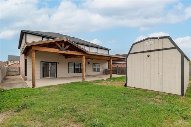 rear view of house featuring a patio, a lawn, a storage shed, ceiling fan, and a fenced backyard