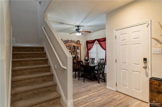 entryway with light wood finished floors, ceiling fan, stairway, and baseboards