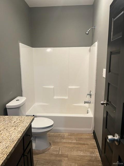 bathroom with toilet, wood finish floors, tub / shower combination, and vanity