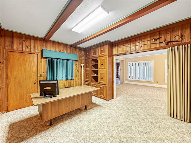 office area featuring wooden walls, beamed ceiling, and light colored carpet