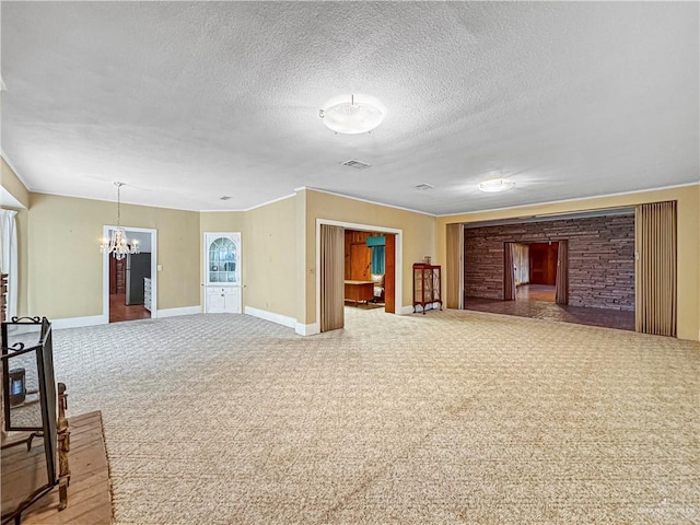 unfurnished living room with carpet, a textured ceiling, and an inviting chandelier