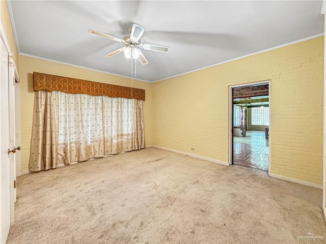 carpeted empty room with crown molding, ceiling fan, and brick wall