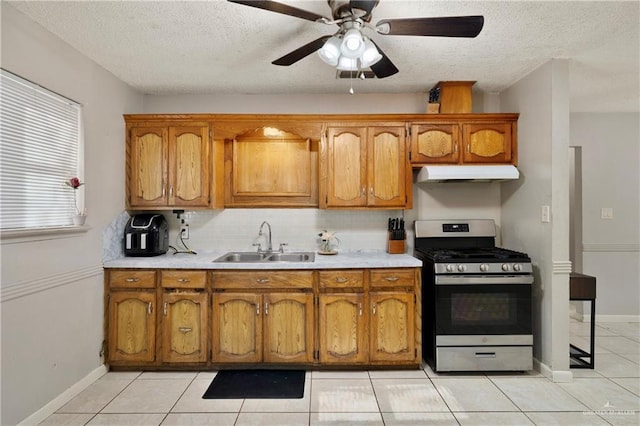 kitchen featuring sink, a textured ceiling, light tile patterned floors, stainless steel range with gas stovetop, and backsplash