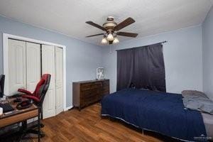 bedroom with dark wood-type flooring, ceiling fan, and a closet