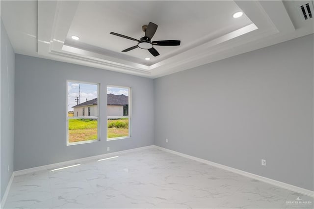 unfurnished room with ceiling fan and a raised ceiling