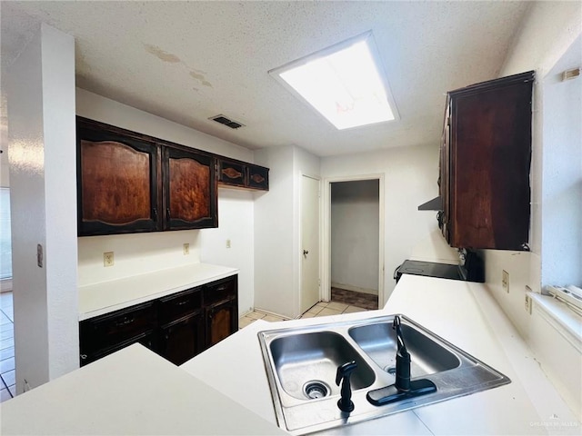 kitchen with range, sink, a skylight, a textured ceiling, and dark brown cabinetry