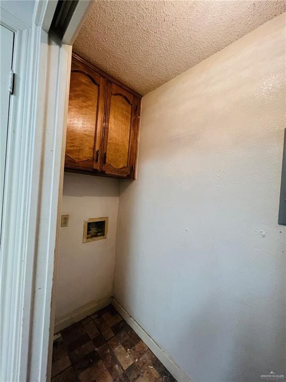 laundry room with cabinets, a textured ceiling, and hookup for a washing machine