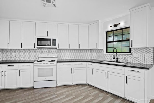 1315 Rio Guadalupe Cir, San Juan, TX 78589 - kitchen with dark countertops, a sink, white electric range, and white cabinetry