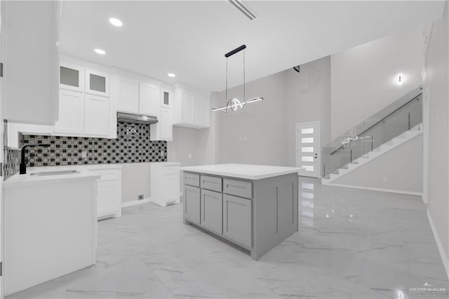 kitchen with a kitchen island, pendant lighting, tasteful backsplash, sink, and white cabinets